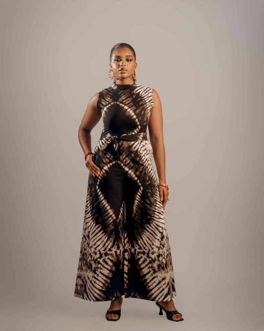 Woman wearing a sleeveless jumpsuit with a tie-dye pattern on a plain background