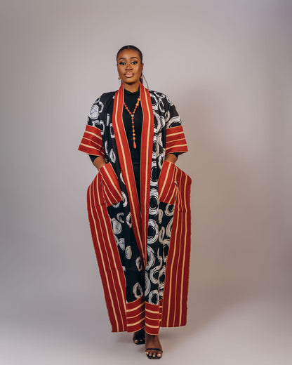 Woman wearing a patterned outfit with a long, open coat against a plain background